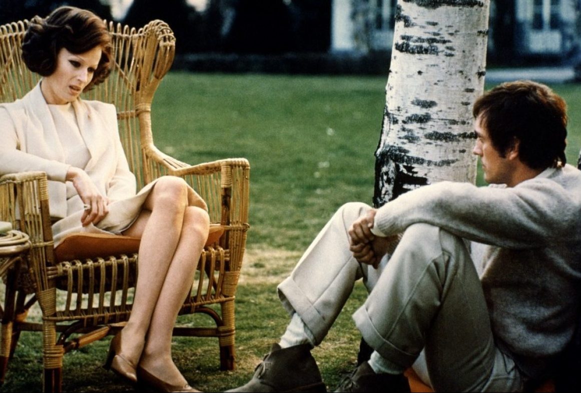 still movie image of two people chatting on a lawn both are seated